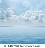 blue sea and cloudy sky over it