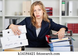 Bored Businesswoman Behind Stacked Binders At Desk