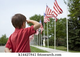 Boy salutes flags at Memorial Day display in a small town