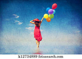 Brunette girl with colour balloons at coast. 