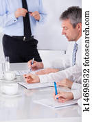 Businesspeople Writing Notes In Meeting