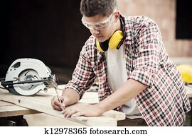 Carpenter measuring a wooden plank Carpenter measuring a wooden plank