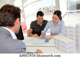 Couple in real-estate agency signing property loan contract