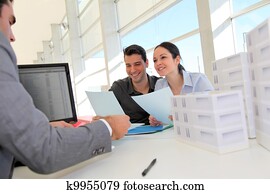 Couple in real-estate agency signing property loan contract