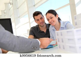 Couple in real-estate agency signing property loan contract