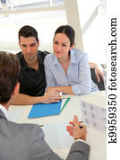 Couple in real-estate agency signing property loan contract