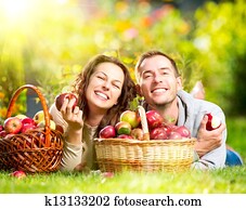 Couple Relaxing on the Grass and Eating Apples in Autumn Garden