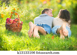 Couple Relaxing on the Grass and Eating Apples in Autumn Garden 