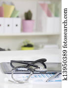Doctor office table desk and black chair with stethoscope  and white paper