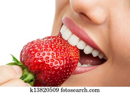Extreme close up of teeth biting strawberry.