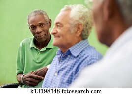 Group of old black and caucasian men talking in park