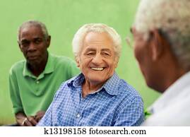 Group of old black and caucasian men talking in park
