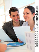 Happy young couple signing property purchase contract 