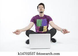 Man meditating infront of a laptop