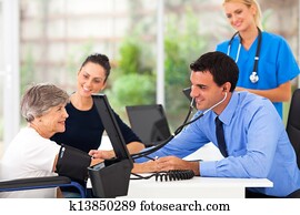 medical doctor taking senior woman's blood pressure