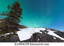Northern Lights Aurora borealis over snowy rocks