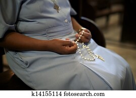 People and religion, catholic sister praying in church and holding cross in hands. With model release