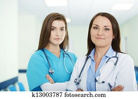 Portrait of young female doctor with intern in background