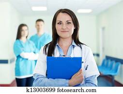 Portrait of young female doctor with interns in background