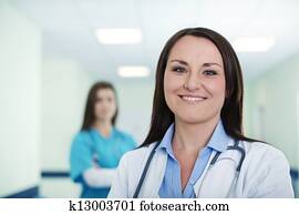 Portrait of young female doctor with intern in background