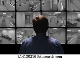 Security guard conducting surveillance by watching several security monitors Security guard conducting surveillance by watching several security monitors