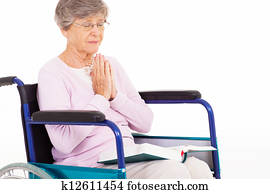 senior woman praying on wheelchair