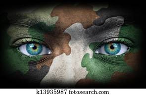 Soldier face with army colors looking from dark Soldier face with army colors looking from dark