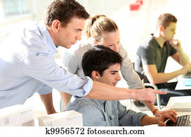 Students with teacher in front of desktop computer