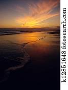 Sunset over beach with lapping waves