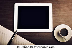 tablet pc and a coffee and notebook with pen on the office desk