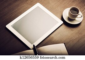 tablet pc and a coffee and notebook with pen on the office desk