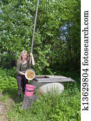 The young woman at a well, pours water in a bucket