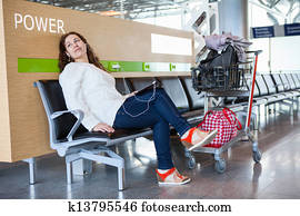 Transit passenger spending time with tablet pc in airport lounge with luggage hand-cart