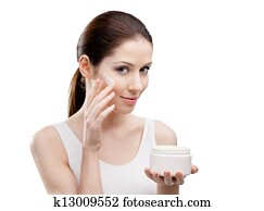 Woman putting on lifting cream from container on face