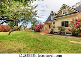 Yellow house exterior with spring blooming rhododendron