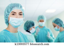 Young female surgeon with medical team in back before surgery Young female surgeon with medical team in back before surgery