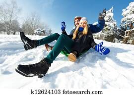 young happy couple sledding in winter young happy couple sledding in winter