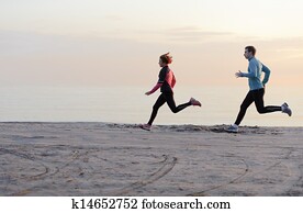 Young man and woman running along the waterfront