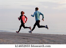 Young man and woman running along the waterfront