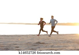 Young man and woman running along the waterfront