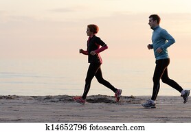 Young man and woman running along the waterfront