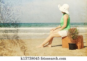 young woman with vintage suitcase om the beach. Photo in old color image style.