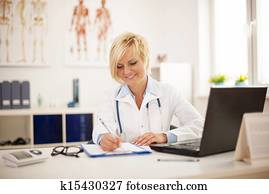 Beautiful young female doctor working at her office