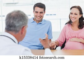 Cheerful couple expecting baby listening to doctor