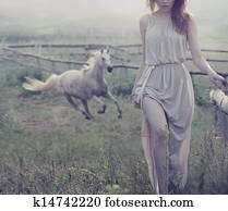 Delicate brunette posing with horse in the background