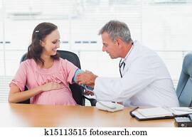 Doctor taking blood pressure of pregnant patient