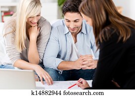 Financial Advisor Explaining Document To Couple At Table Financial Advisor Explaining Document To Couple At Table
