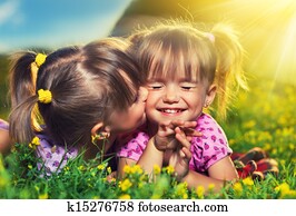 happy family. little girls twin sisters kissing and laughing in the summer outdoors happy family. little girls twin sisters kissing and laughing in the summer outdoors