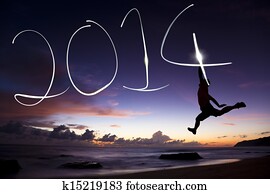 happy new year 2014.young man jumping and drawing 2014 by flashlight