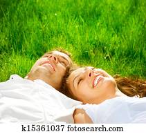 Happy Smiling Couple Relaxing on Green Grass. Park